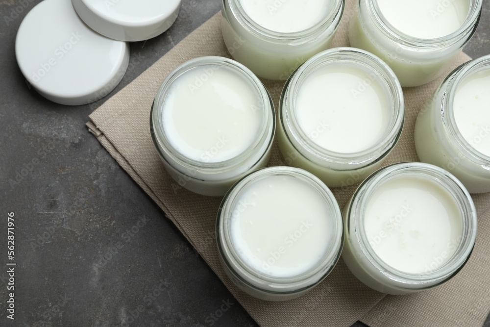 Tasty yogurt in glass jars on grey table, flat lay Tasty yogurt in glass jars on grey table, flat lay