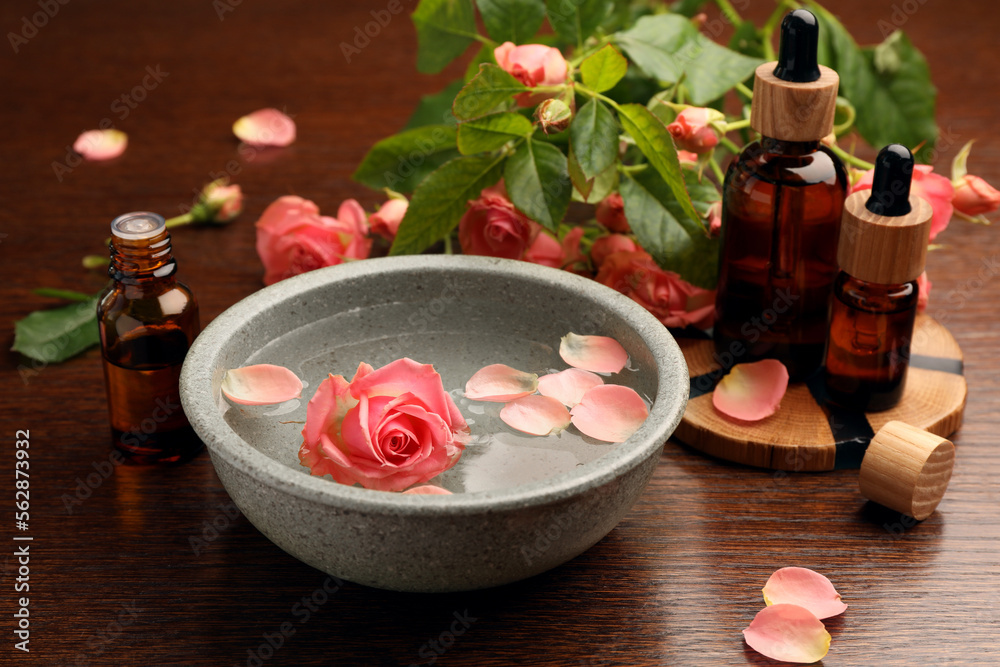 Bowl of water, bottles with essential oil and beautiful rose petals on wooden table. Aromatherapy treatment Bowl of water, bottles with essential oil and beautiful rose petals on wooden table. Aromatherapy treatment