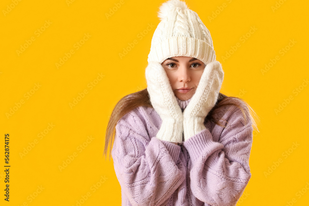Frozen young woman in winter clothes on yellow background, closeup Frozen young woman in winter clothes on yellow background, closeup