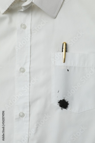 White shirt with stain of black ink and pen in pocket, top view photo