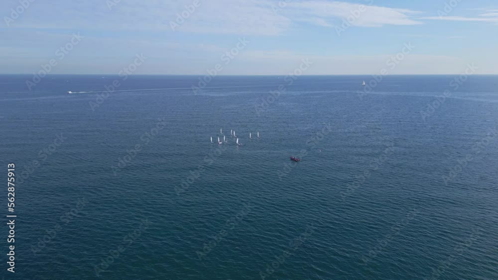 Camera approaching a bunch of boats in open sea Junior sailors sport competition. Junior yacht club regatta in the open sea. Junior training course on sailboats. Aerial drone video. Camera approaching a bunch of boats in open sea Junior sailors sport competition. Junior yacht club regatta in the open sea. Junior training course on sailboats. Aerial drone video.