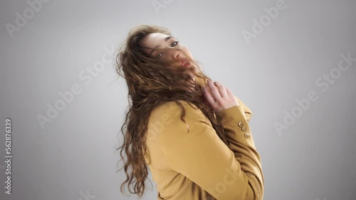 Portrait of young woman posing and fooling around and playing with hair on camera. Theme of models and photoshoots in studio on white background. Positive emotion and good mood of professional actress