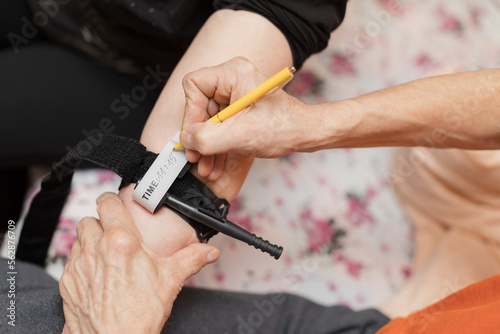 Writing a time on applied tourniquet - caucasian older man