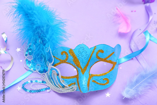 Carnival mask with confetti and feathers on lilac background