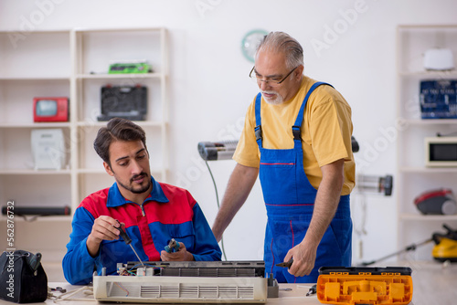 Two male repairmen repairing air-conditioner © Elnur