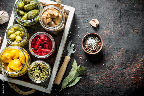 Jars of various preserved vegetables on tray.