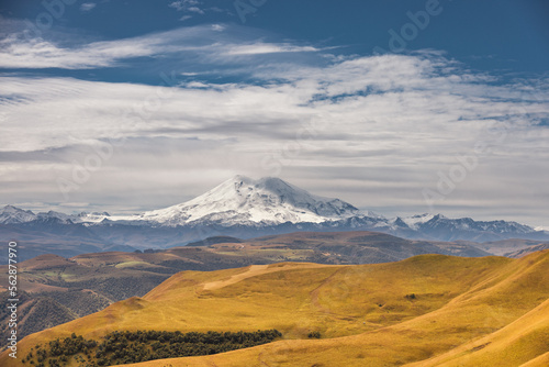 Big mountain Elbrus against the blue sky. View from a large plateau and steep cliffs.