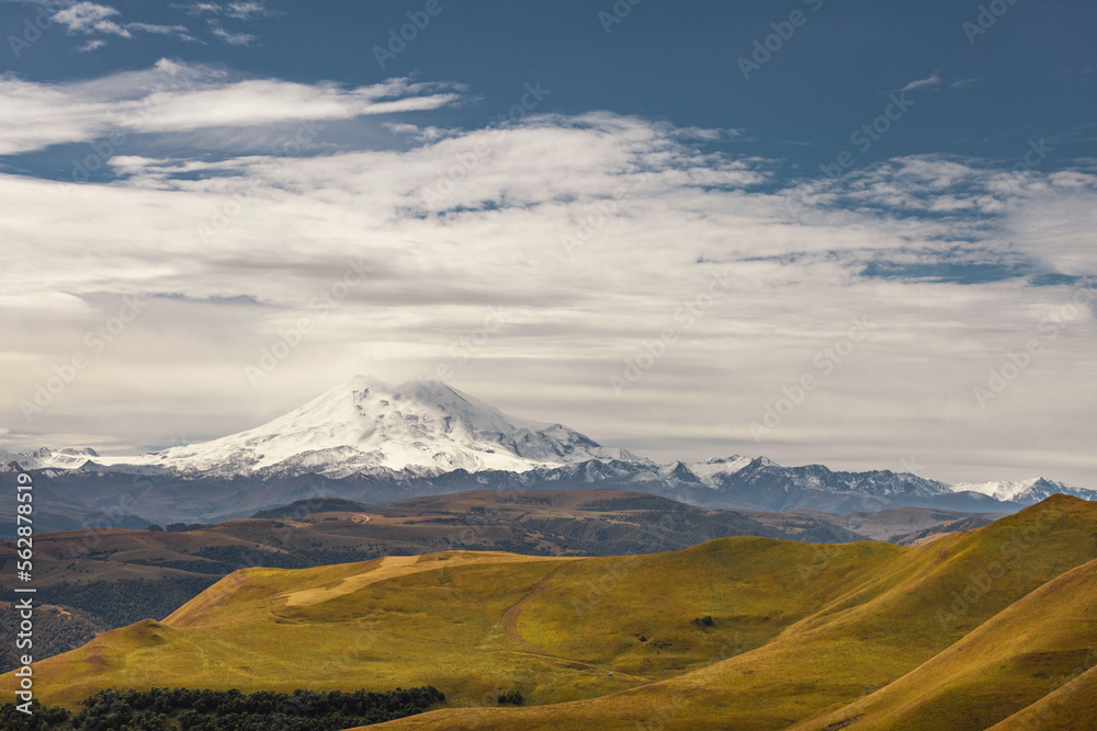 Big mountain Elbrus against the blue sky. View from a large plateau and steep cliffs.