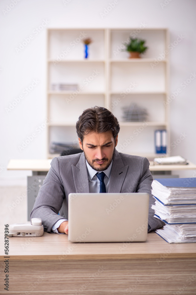 Young male employee and too much work in the office Young male employee and too much work in the office