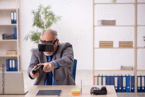 Old male employee enjoying virtual glasses at workplace