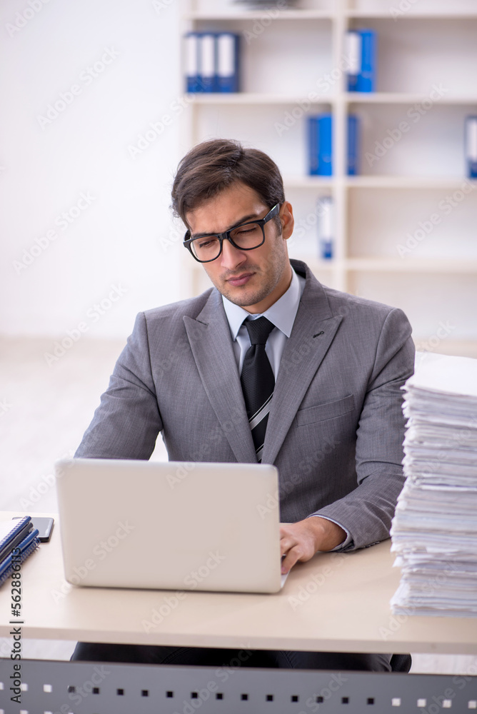 Young male employee and too much work in the office Young male employee and too much work in the office