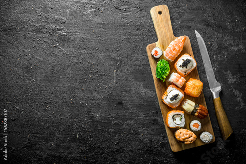 Set of different types of sushi and rolls on wooden cutting Board.