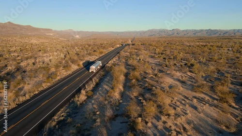 Supply chain trucker drives 18 wheeler semi truck though southwest Arizona Joshua trees lined desert in logistics transportation video