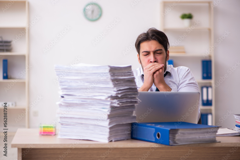 Young businessman employee unhappy with excessive work in the office Young businessman employee unhappy with excessive work in the office