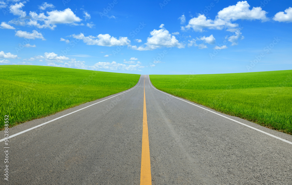 Strait tarmac road in slope grass field with blue sky background. Strait tarmac road in slope grass field with blue sky background.