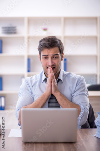 Young male employee unhappy with excessive work in the office