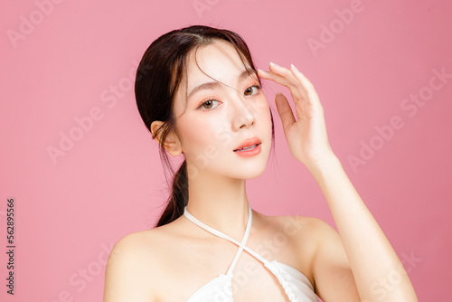 Fotografie, Obraz Young Asian woman gathered in ponytail with natural makeup on face have plump lips and clean fresh skin wearing white camisole on isolated pink background