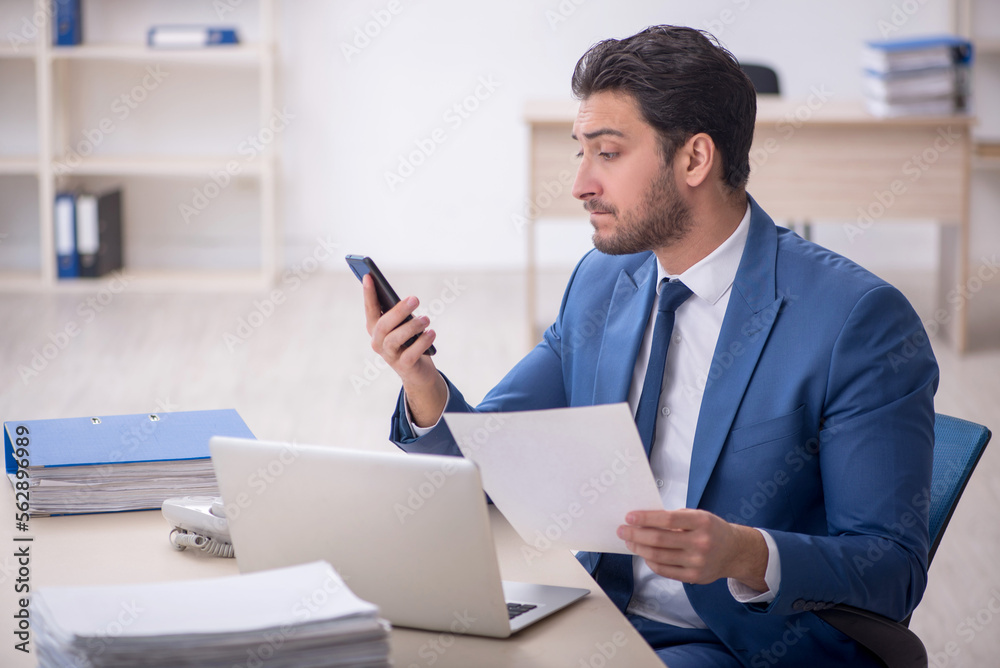 Young male employee and too much work in the office Young male employee and too much work in the office