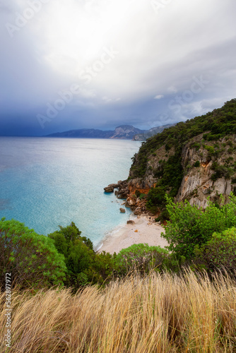 Sandy Beach on a rocky coast near Cala Gonone, Sardinia. Cloudy Sunrise Sky.