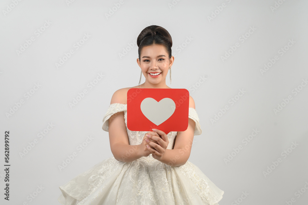 Asian beautiful bride smiling and posing with heart sign on white background