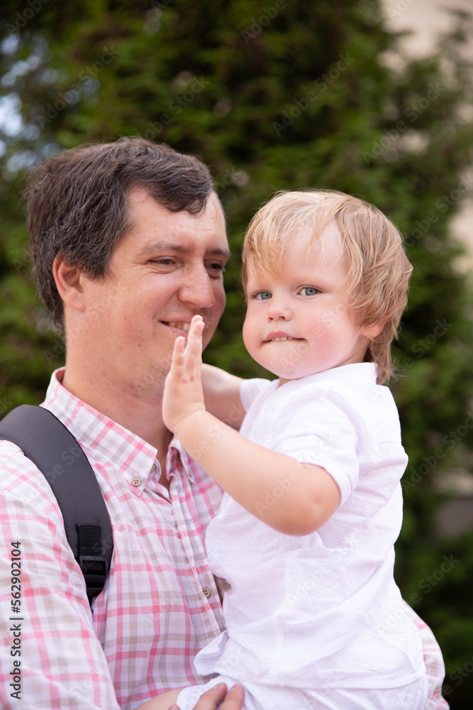 the father holds his son in his arms and hugs him. a man with a boy on the street hugging the father holds his son in his arms and hugs him. a man with a boy on the street hugging