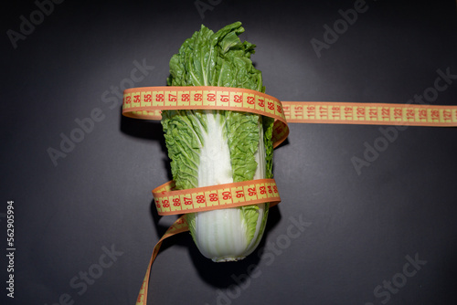 Napa cabbage in centimeter tape measure on the black background; Weight loss food; Healthy food; Diet food photo