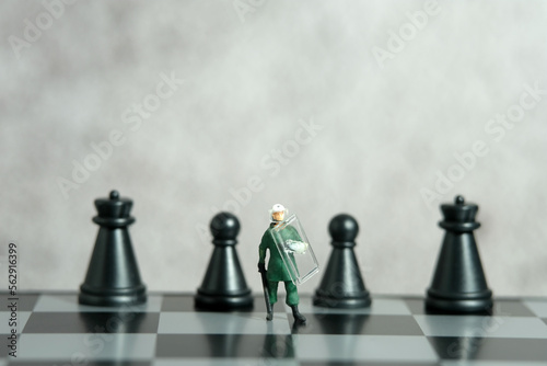Miniature people toy figure photography. Protection strategy concept. A military anti riot armored army standing above chessboard
