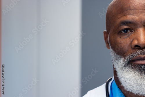 Half face portrait of african american senior male doctor in hospital corridor, copy space photo