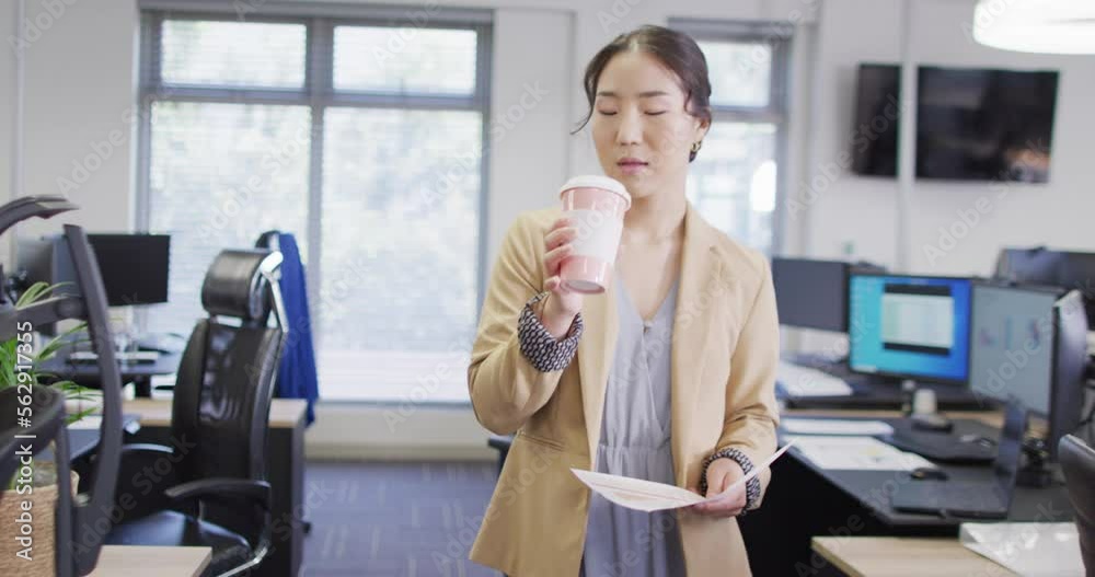 Biracial businesswoman drinking coffee in office, slow motion Biracial businesswoman drinking coffee in office, slow motion