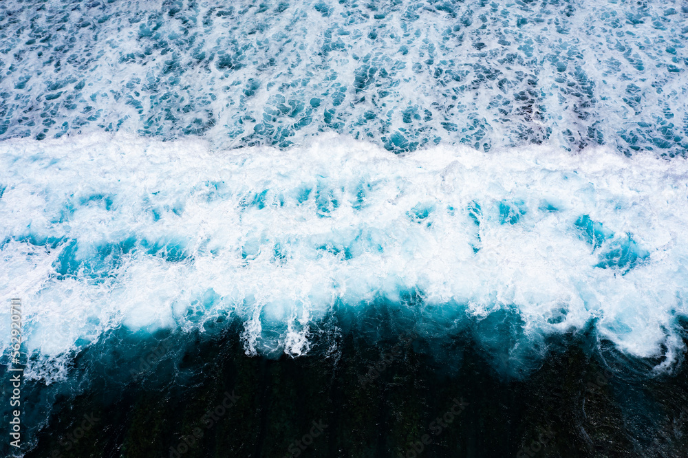 Stunning aerial view of some ocean waves breaking on a blue sea. Crushing waves, ocean waves relaxation. Bali, Indonesia.