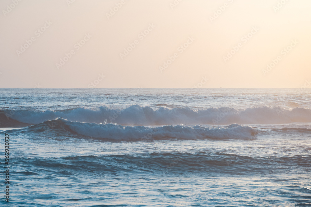 (Selective focus) Stunning view of some ocean waves breaking on the shore during a beautiful sunset. Crushing waves, ocean waves relaxation. Bali, Indonesia.