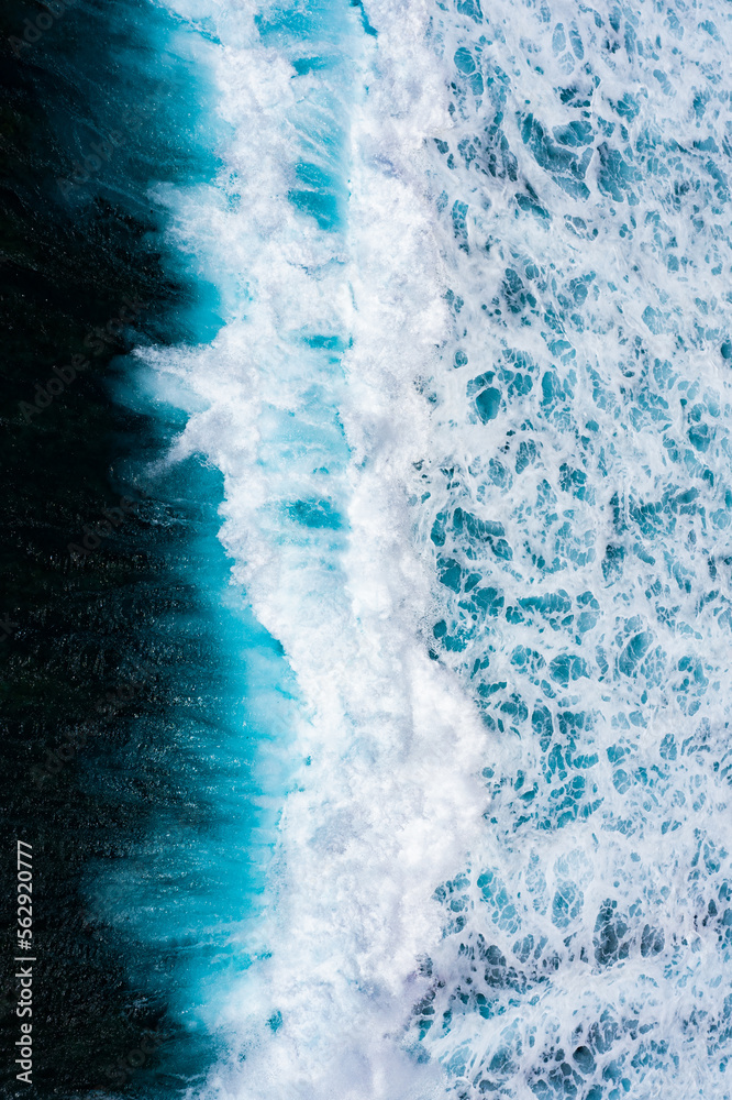 Stunning aerial view of some ocean waves breaking on a blue sea. Crushing waves, ocean waves relaxation. Bali, Indonesia.