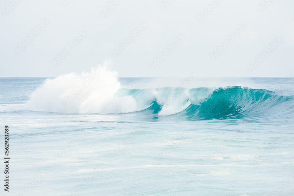 (Selective focus) Stunning view of some ocean waves breaking on the shore during a beautiful sunny day. Crushing waves, ocean waves relaxation. Bali, Indonesia.