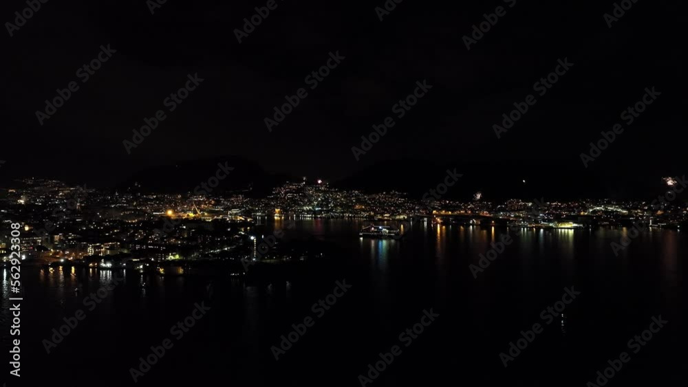 A ship is leaving port of Bergen while fireworks is seen all over the city during new year celebration - Panoramic night aerial - Norway A ship is leaving port of Bergen while fireworks is seen all over the city during new year celebration - Panoramic night aerial - Norway