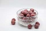 Beautiful small vintage lead crystal bowl containing hard raspberry candies, on white background with copy space