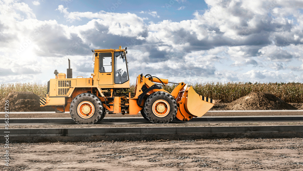 Bulldozer or loader at a construction site shovels mountain soil into a heap. Powerful wheel loader or bulldozer with a large bucket at a construction site. Construction equipment for earthworks.