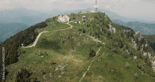 Drone shot of the mountain Uršlja sunbasking in sun, camera rotating down towards the road which is leading at the top. Clouds and valley in the background. photo