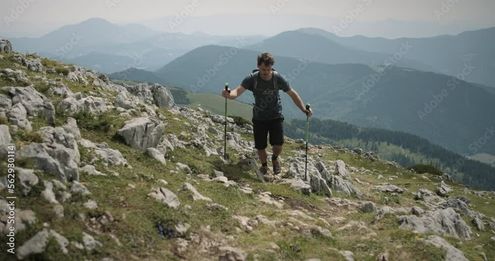 Hiker climbin on the mountain Raduha towards the camera, valley and other mountains visible in the background, partially cloudy. Hiker climbin on the mountain Raduha towards the camera, valley and other mountains visible in the background, partially cloudy.
