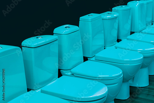 A row of white toilets. View from the side against a dark background.