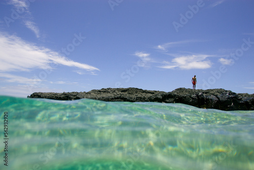 A man stands on a volcanic rock on the shore of Lumahai Beach, Kauai, Hawaii (water housing) photo