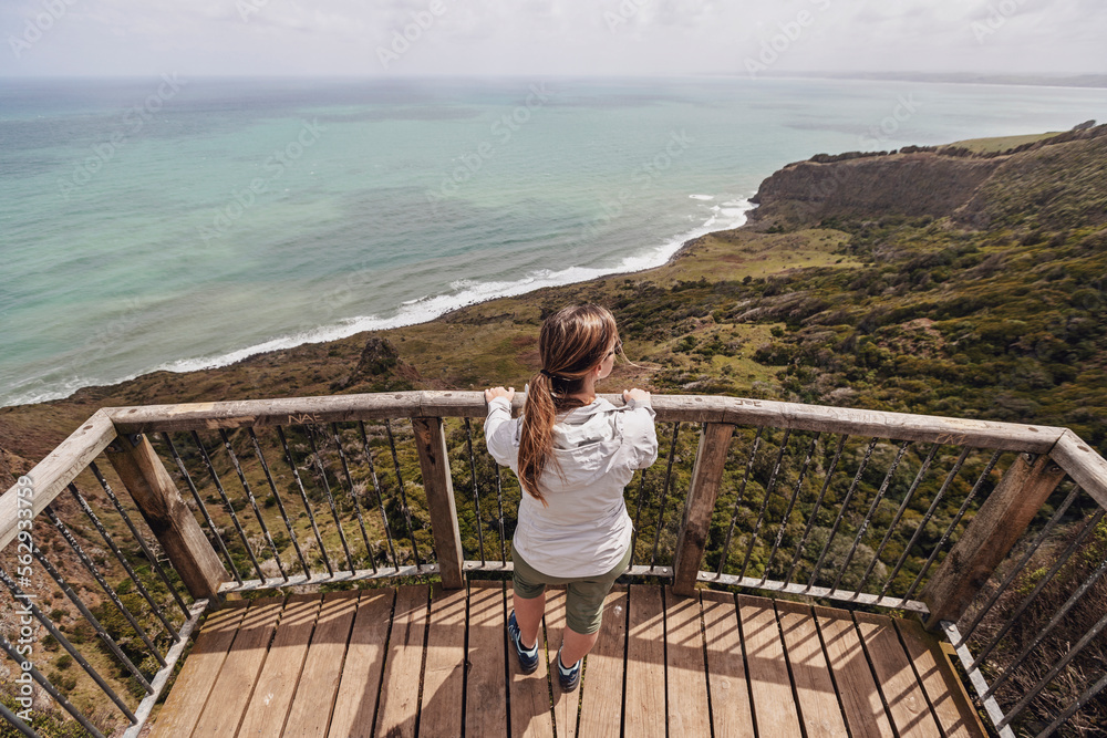 © Cavan Images - Female looks out at ocean from high viewpoint, Raglan, New Zealand