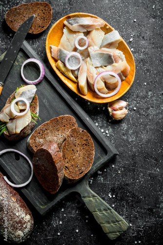 Fillet of salted herring on a piece of bread and onions.