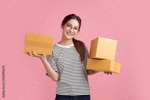 Beautiful Young Asian woman holding parcel box isolated on pink background, Delivery courier and shipping service concept. photo