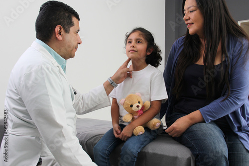 Foto Latina mother cares for and accompanies her curly little daughter at the dark-ha