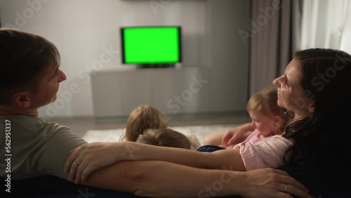 Dad, mom, three kids and their chihuahua dog are sitting on the couch and want to watch TV. Children bicker and do not sit still. Evening movie viewing by a large friendly family, Europeans. 4k 