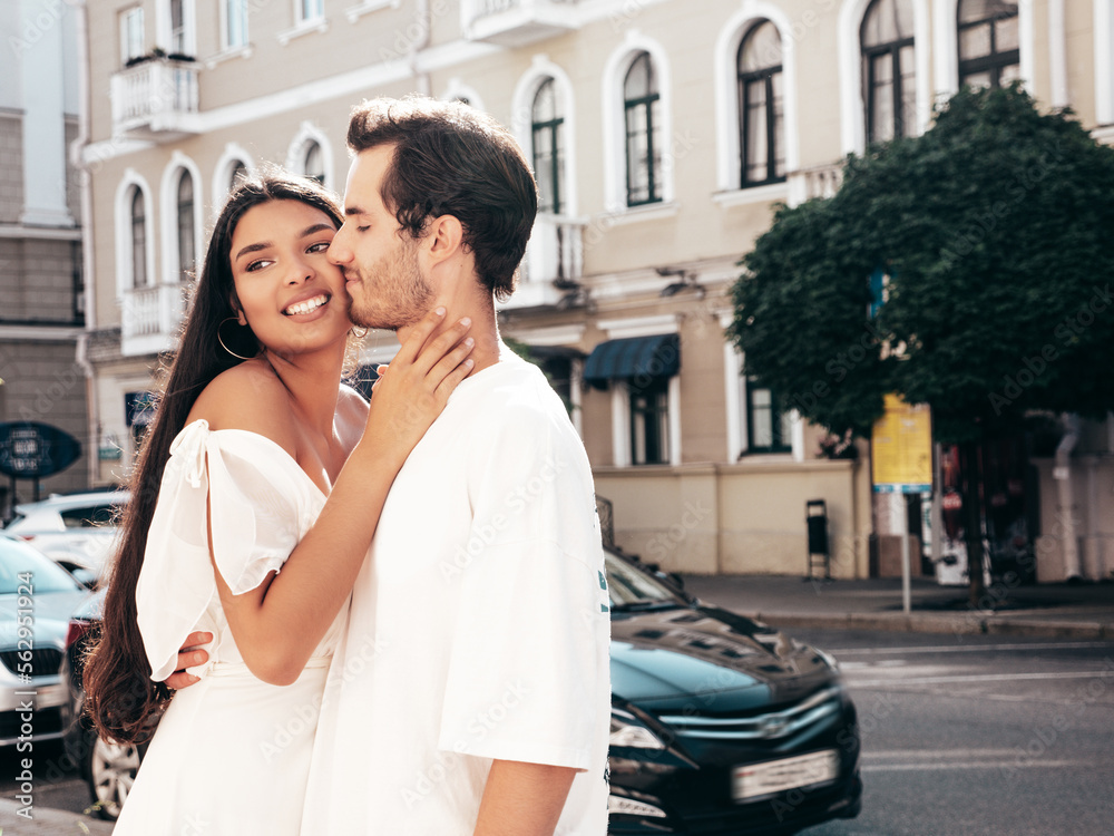 Smiling beautiful woman and her handsome boyfriend. Happy cheerful family. Sexy couple posing in street at sunrise. During romantic date at sunny summer day outdoors. Looking at each other. Kissing