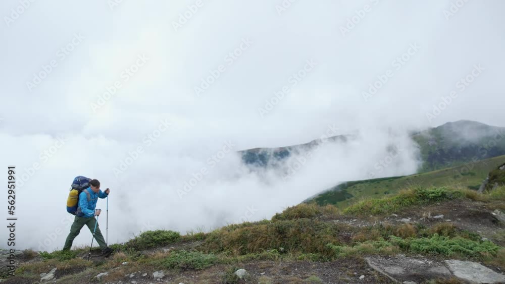 A tourist with a backpack goes on a hike along a mountain range above the clouds. The concept of freedom of victory and happiness is higher than the sky. High quality 4k footage A tourist with a backpack goes on a hike along a mountain range above the clouds. The concept of freedom of victory and happiness is higher than the sky. High quality 4k footage
