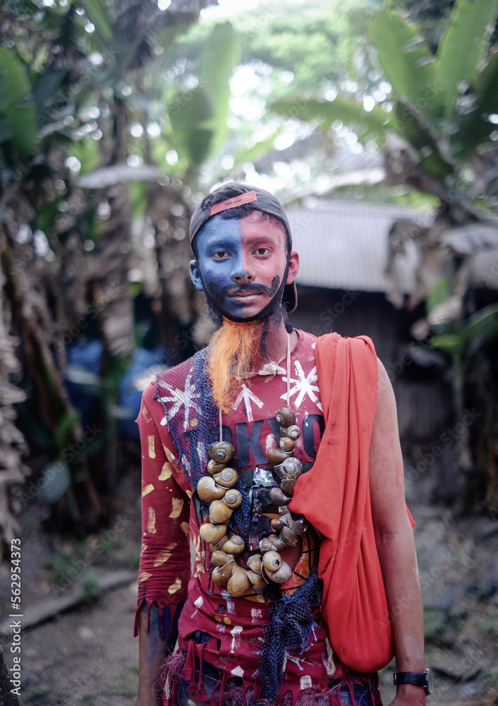 South asian young hindu religious boy wearing a wreath of dry snails and take makeup of a mad man in gajan festival 
