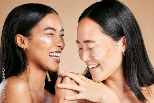 Happy, beauty and skincare women with cream for face isolated on a beige studio background. Wellness, smile and Asian model friends with sunscreen for love of cosmetics and dermatology on a backdrop photo
