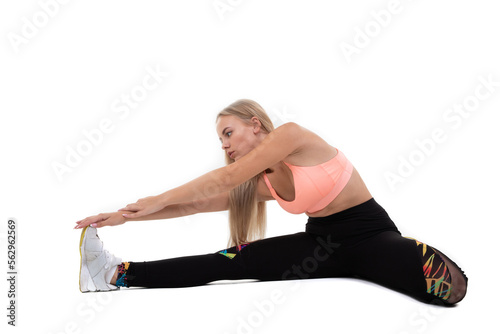 A sporty young woman in a pink top, leggings and sneakers does exercises on a white background